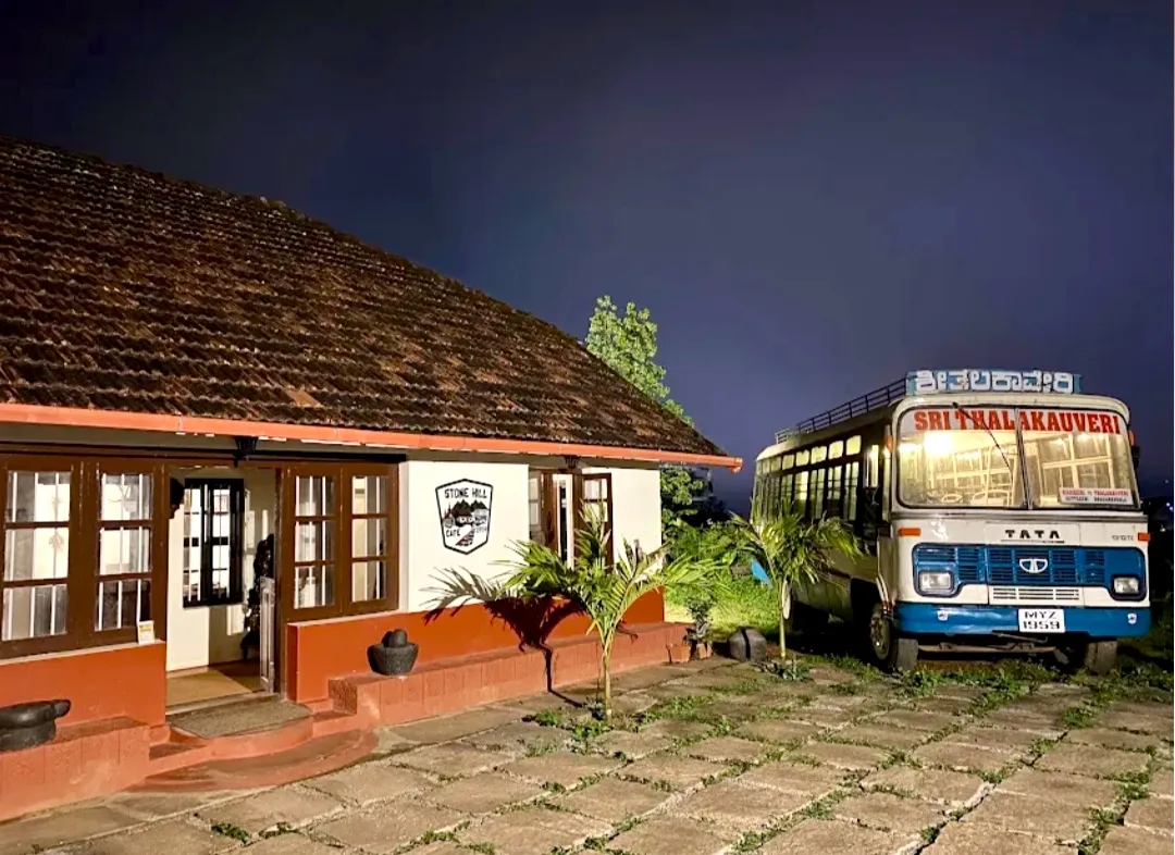 The building at dusk with the blue and white bus parked alongside it.